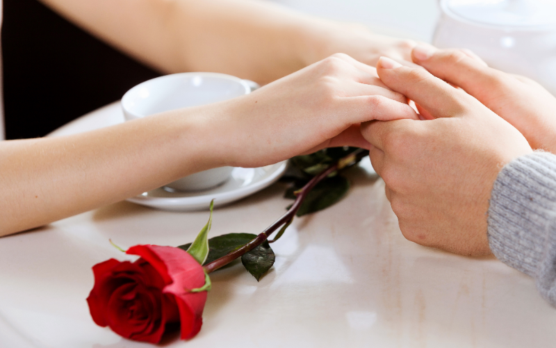 手を繋いでいるカップルの横にあるバラ